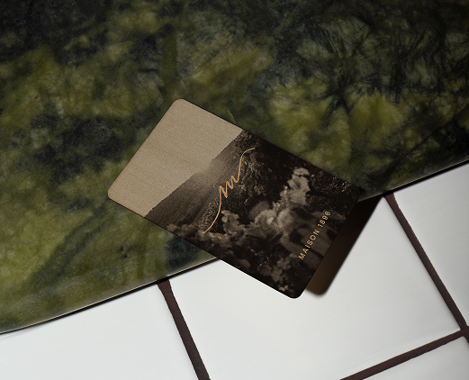 Maison 1896 room keycard with gold monogram on a green marble surface