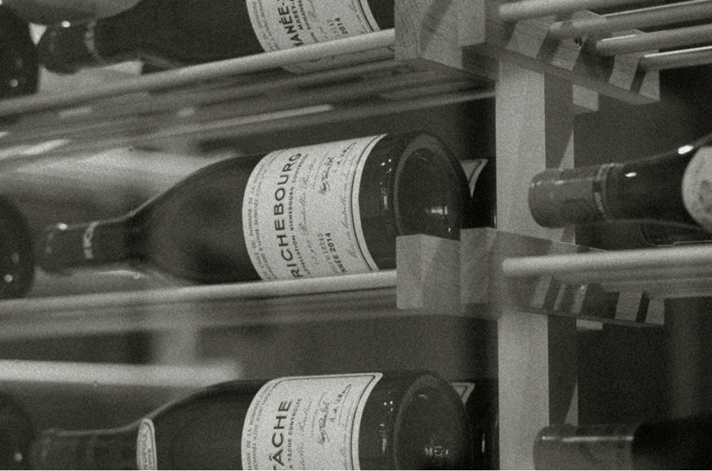 Burgundy bottles including Richebourg resting in a wooden cellar rack