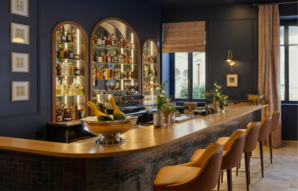 Maison 1896 bar with arched liquor displays, brass sconces, and leather stools